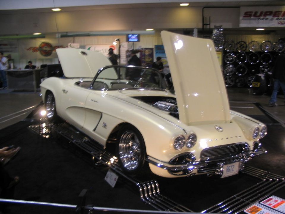 Cream 1958 Chevrolet Corvette convertible with hoods open, showing engine. Chrome wheels and trim