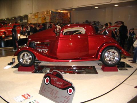 1993 Ford Taurus - A custom red hot rod coupe, identified as 'Empty Pockets', is showcased with its hood open, revealing the engine and polished chrome detail…