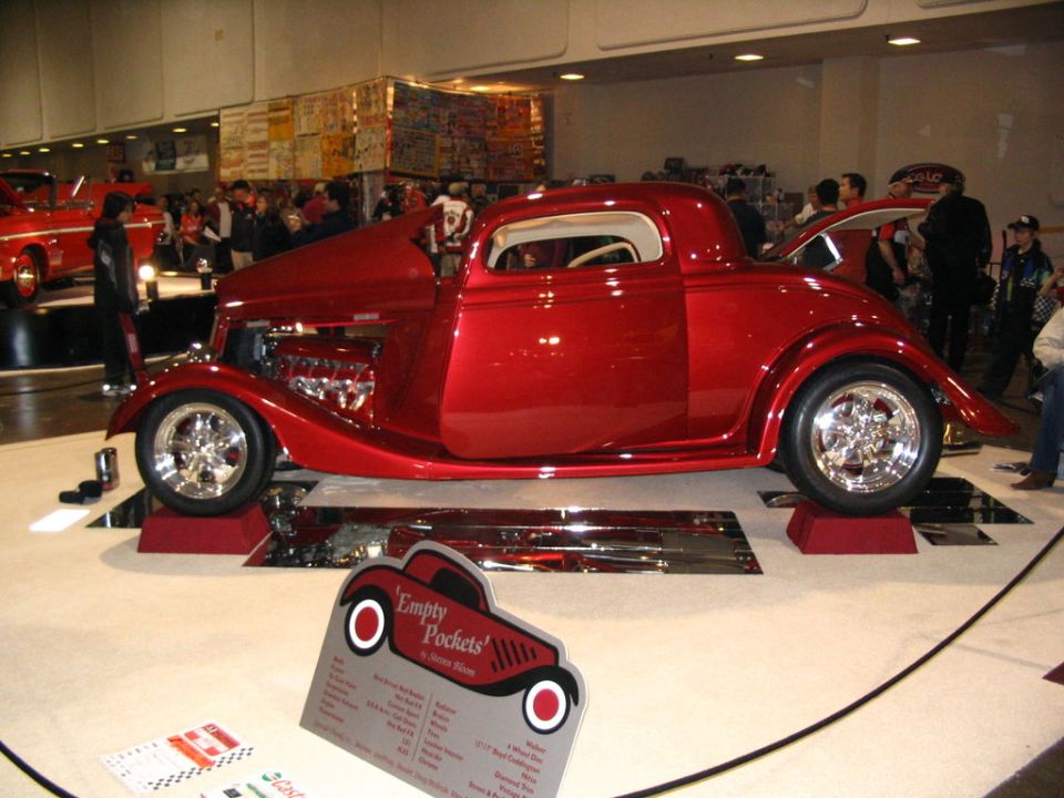 Red hot rod coupe with exposed engine and custom wheels on display