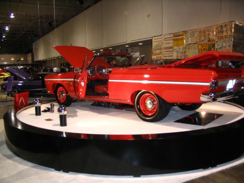 1993 Ford Taurus - A classic red convertible is showcased indoors with its hood and door open, while other vehicles are visible in the background.