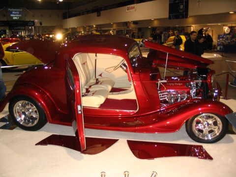 1993 Ford Taurus - Custom red hot rod coupe displayed with open doors and hood, revealing its custom interior and engine. Detached body panels are visible on…