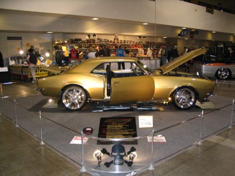 1993 Ford Taurus - A custom gold 1967 Chevrolet Camaro is showcased with its doors and hood open at an indoor event.