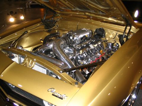 1993 Ford Taurus - The engine bay of a gold Chevrolet features a polished V8 engine with a prominent supercharger and chrome intake.