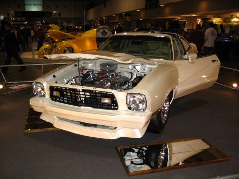 1993 Ford Taurus - Front view of a modified 1975 Ford Mustang II at a car show, with another vehicle behind it.