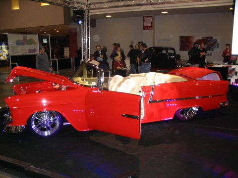 1993 Ford Taurus - A bright red convertible, likely a 1955 model, is displayed with its hood and driver's door open, revealing a white interior and chrome whe…