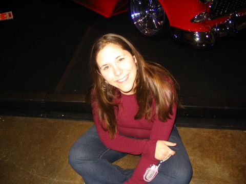1993 Ford Taurus - A woman poses for a photo in front of a custom red car with shiny chrome wheels.