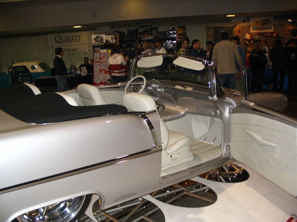 Interior of a silver custom convertible with white seats and black top, doors open