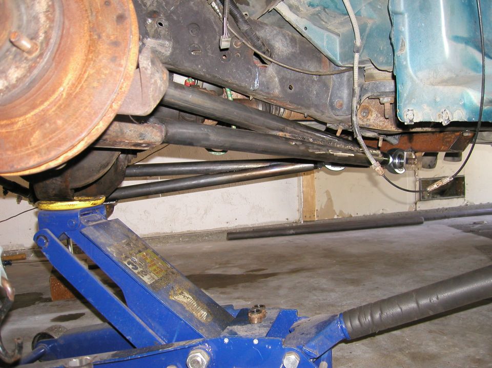Undercarriage with suspension components and a blue jack. Text reads SUPERMOTORS.NET