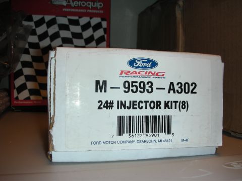 1998 Ford Crown Victoria - Ford Racing Performance Parts box labeled M-9593-A302 24# Injector Kit (8) sits on a counter near a checkered-flag backdrop.
