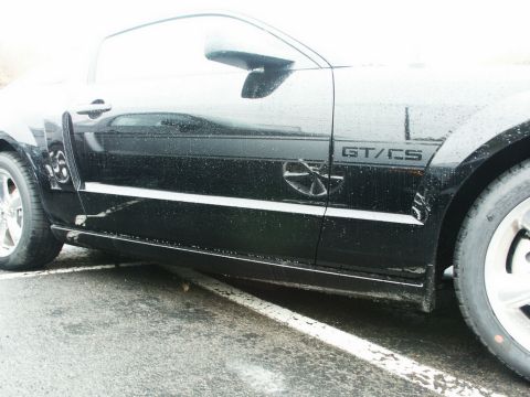 2001 Mercury Grand Marquis - Side view of a black car with GT/CS badging and a circular emblem, showing water droplets on the surface.