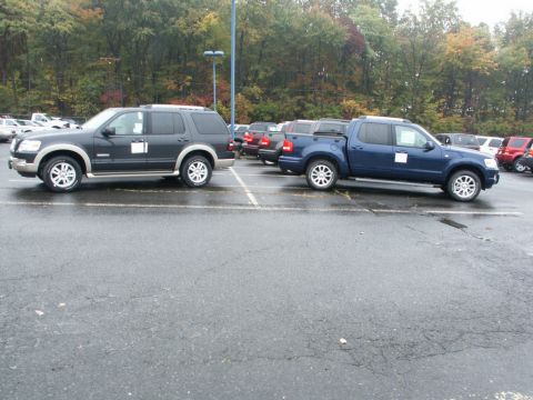 2001 Mercury Grand Marquis - A dark gray SUV and a blue pickup truck are parked side-by-side in a lot on an overcast day.