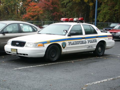 2001 Mercury Grand Marquis - A white 2001 Mercury Grand Marquis police car is parked in a lot, with "PLAINFIELD POLICE" visible on its side.
