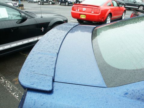 2001 Mercury Grand Marquis - A blue Ford Mustang's rear spoiler is visible, with a black Mustang and a red Mustang in the background.