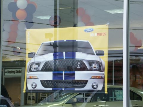 2001 Mercury Grand Marquis - A banner advertising a Ford Mustang is displayed in a dealership window.