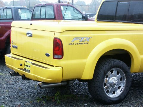 2001 Mercury Grand Marquis - Rear view of a yellow pickup truck with "FX4 ALL TERRAIN" badging and dual exhaust. Another truck is parked behind.