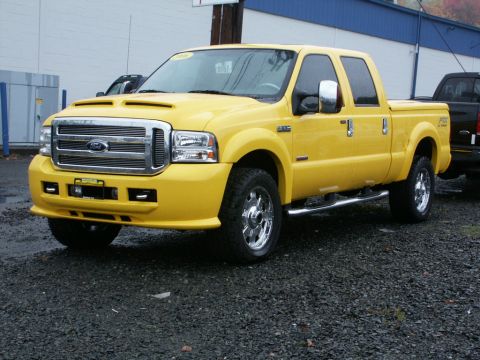 2001 Mercury Grand Marquis - A yellow Ford F-250 Super Duty truck is parked on a gravel lot.