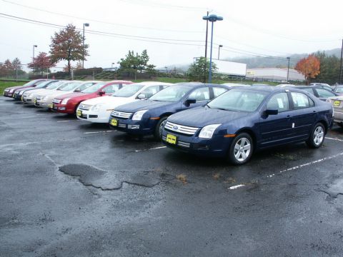 2001 Mercury Grand Marquis - Several Ford Fusion sedans are lined up in a parking lot on an overcast day.