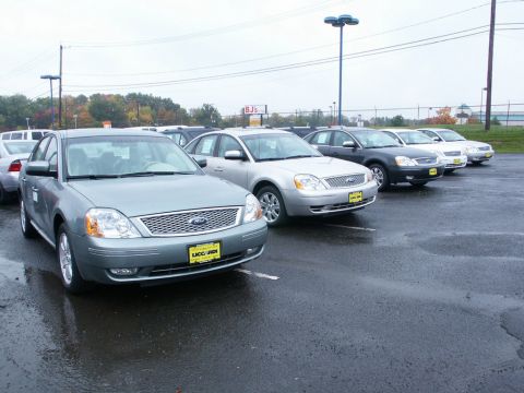 2001 Mercury Grand Marquis - Several sedans are parked in a lot under an overcast sky.