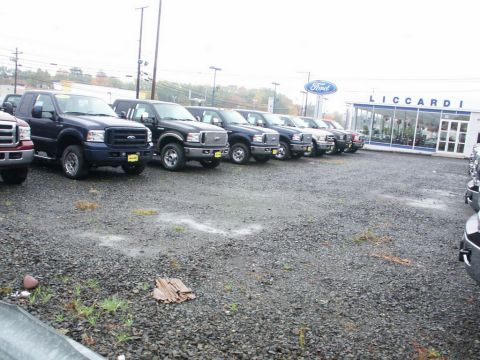 2001 Mercury Grand Marquis - Several Ford trucks are parked in a lot in front of a dealership building.