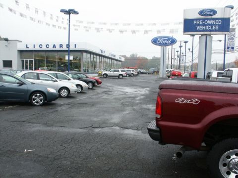 2001 Mercury Grand Marquis - A red pickup truck with a 4x4 decal is parked in the lot of Liccardi Ford, a pre-owned vehicle dealership.