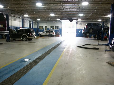 2001 Mercury Grand Marquis - Multiple vehicles are present in a car repair shop, some on lifts and others on the floor.
