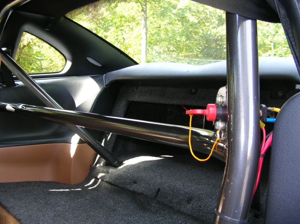 Interior of a 1995 Ford Mustang with a roll cage, tan door panel, and grey carpet