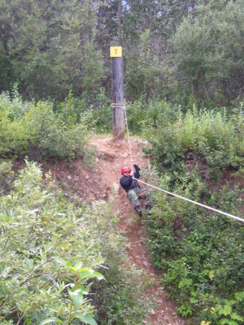 2003 Jeep TJ - A person is rappelling down a wooded slope using a rope, with a marker '7' on a post.