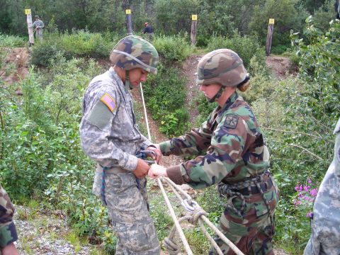 2003 Jeep TJ - Soldiers are seen outdoors in a wooded area, with one soldier assisting another with rope equipment.