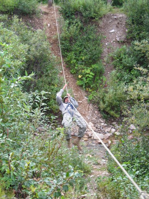 2003 Jeep TJ - A soldier in camouflage rappels down a steep, wooded incline using a rope.