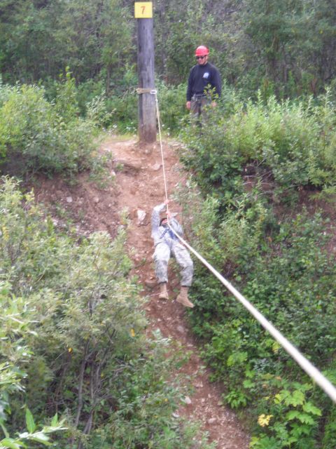 2003 Jeep TJ - A person rappels down a wooded slope, guided by a rope and watched by an instructor.