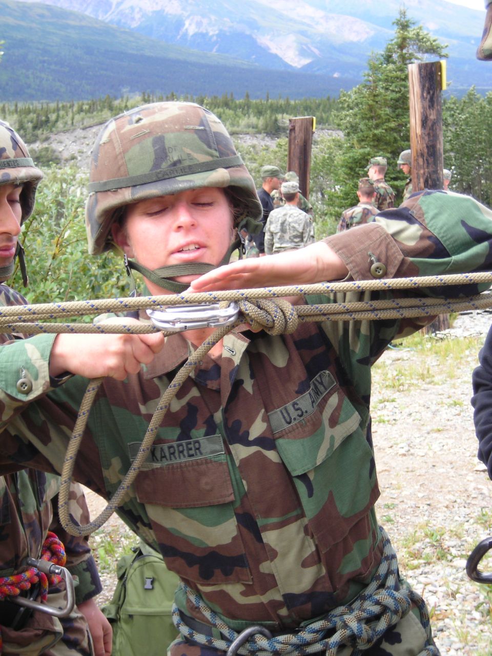 Soldiers in camouflage uniforms practicing rappelling with ropes and carabiners