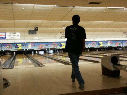 2001 Mercury Grand Marquis - A person walks away from the camera in a bowling alley, with lanes and scoring machines visible.