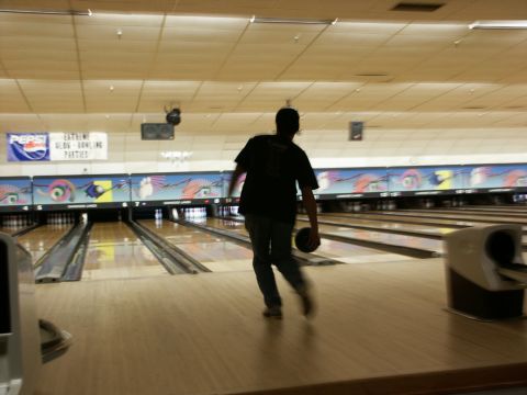 2001 Mercury Grand Marquis - A person bowls in a brightly lit bowling alley, with lanes and pins visible in the background.