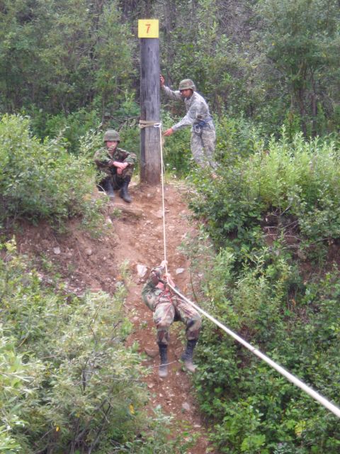 2003 Jeep TJ - Military personnel participate in a training exercise involving rappelling down a steep, wooded incline.