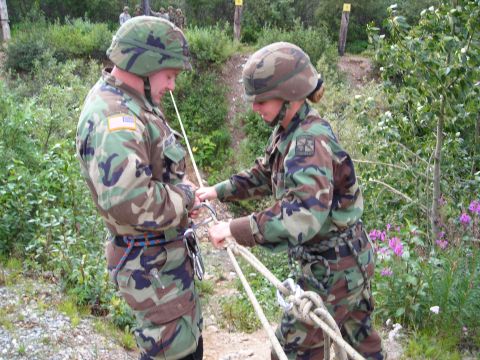 2003 Jeep TJ - Two soldiers in camouflage uniforms are engaged in a rope handling exercise, with carabiners and ropes visible.