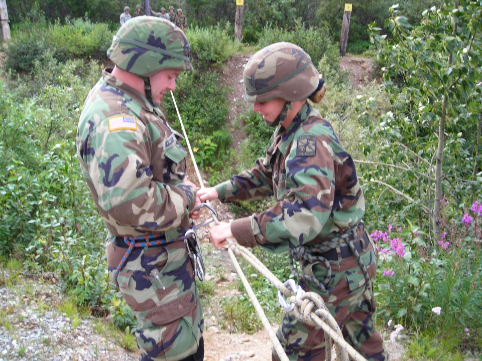 Military personnel practicing rope handling outdoors