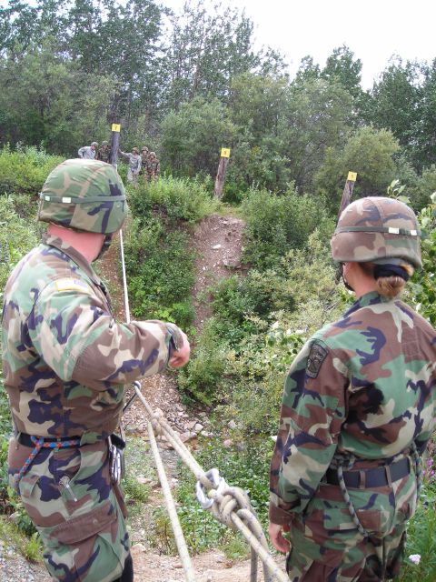 2003 Jeep TJ - Soldiers prepare to navigate an obstacle course with ropes and targets in the background.
