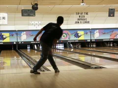 2001 Mercury Grand Marquis - A person bowls in a dimly lit bowling alley with "Oakwood Lanes" signage visible on the scoring machines.