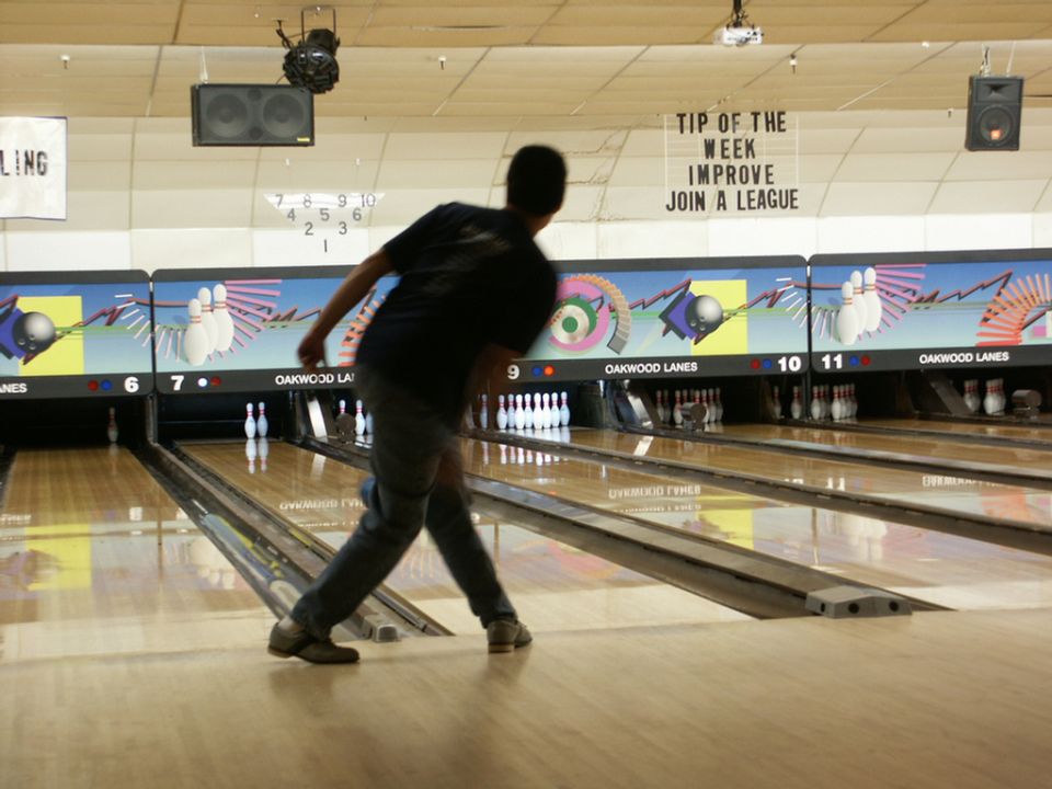 Bowling alley with lanes, pins, and a person bowling. "Oakwood Lanes" is visible