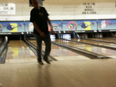 2001 Mercury Grand Marquis - A person laughs while standing on the approach at a bowling alley, with lanes and pins in the background.