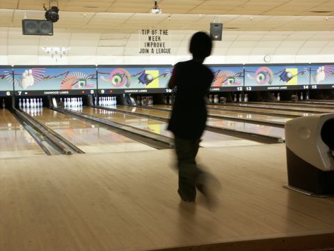 2001 Mercury Grand Marquis - A person bowls in a dimly lit bowling alley, with lane numbers and colorful graphics visible on the back wall.