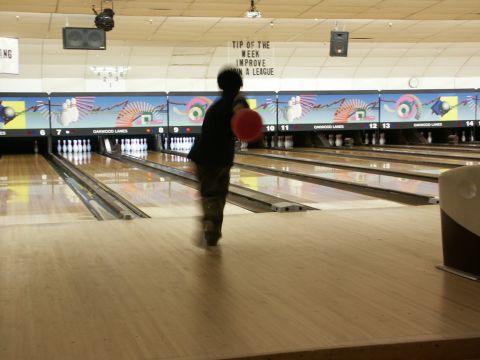 2001 Mercury Grand Marquis - A person bowls a red ball down a lane in a bowling alley, with lane numbers and graphics visible.
