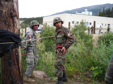 2003 Jeep TJ - Two soldiers are engaged in a rappelling exercise, with a building and mountainous terrain visible in the distance.