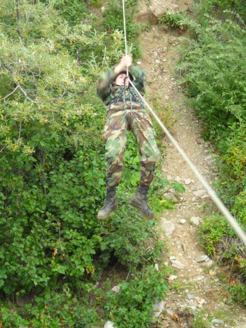 2003 Jeep TJ - A person rappels down a steep, overgrown hillside using a rope.