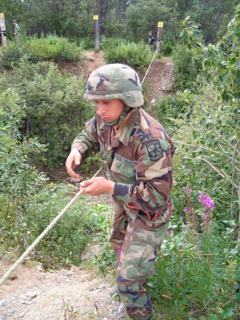2003 Jeep TJ - A soldier practices rappelling down a wooded incline, with targets visible in the background.