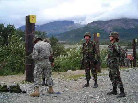 2003 Jeep TJ - Soldiers participate in an outdoor training exercise with mountainous terrain in the background.