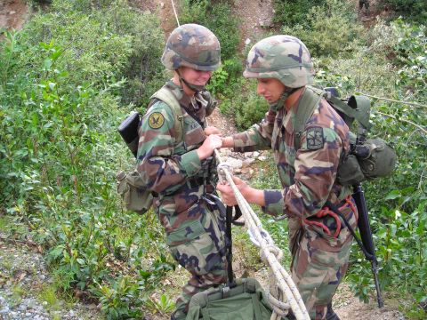 2003 Jeep TJ - Two soldiers in camouflage uniforms and helmets are seen rappelling with ropes on a wooded hillside.