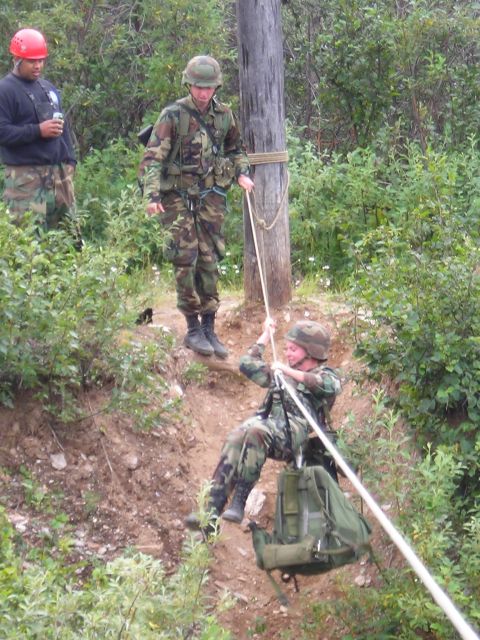 2003 Jeep TJ - Soldiers practice rappelling down a steep, wooded slope using ropes and a wooden pole for support.