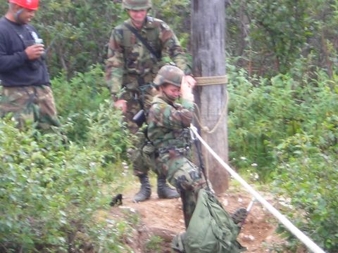 2003 Jeep TJ - Soldiers in camouflage uniforms are engaged in a training exercise involving a wooden pole and ropes, with one individual secured by the ro…