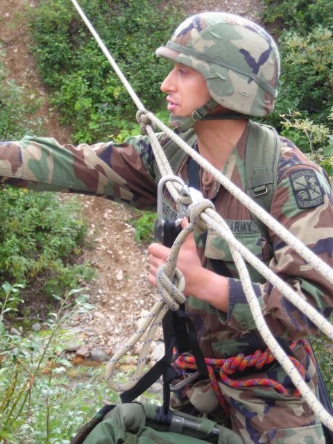 2003 Jeep TJ - A soldier in camouflage gear is seen rappelling down a slope, secured by ropes and harnesses.